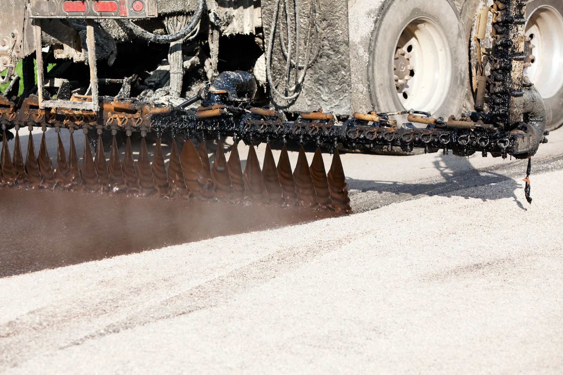 A black sealcoat is being applied to a street by a professional sealcoating company.