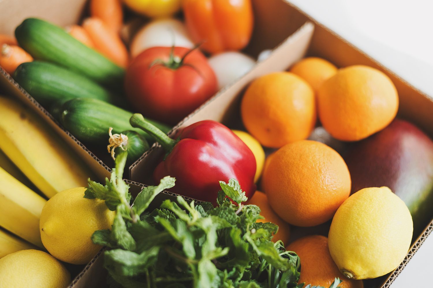 A cardboard box filled with fruits and vegetables.