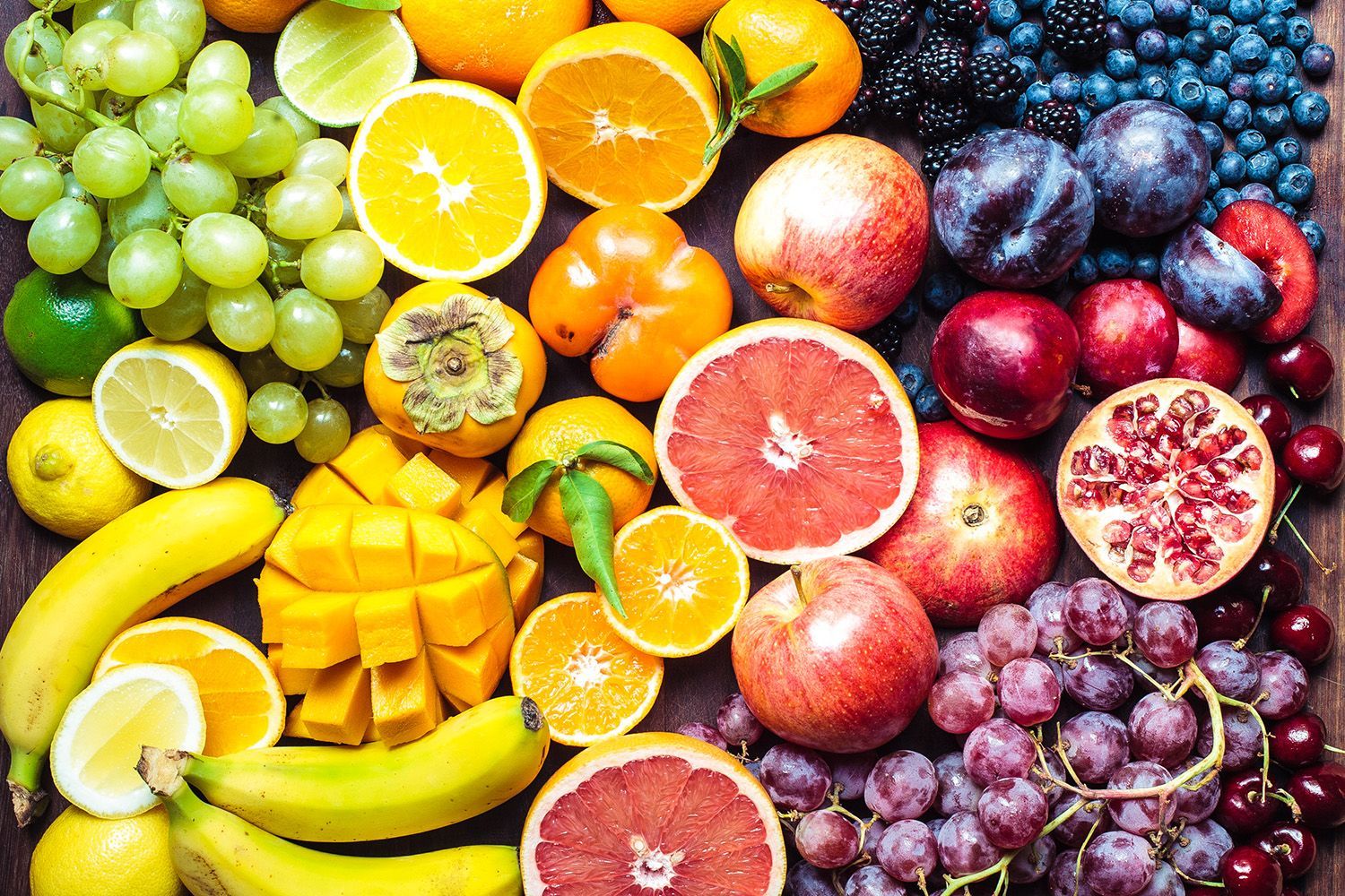 A variety of fruits and berries on a wooden table.