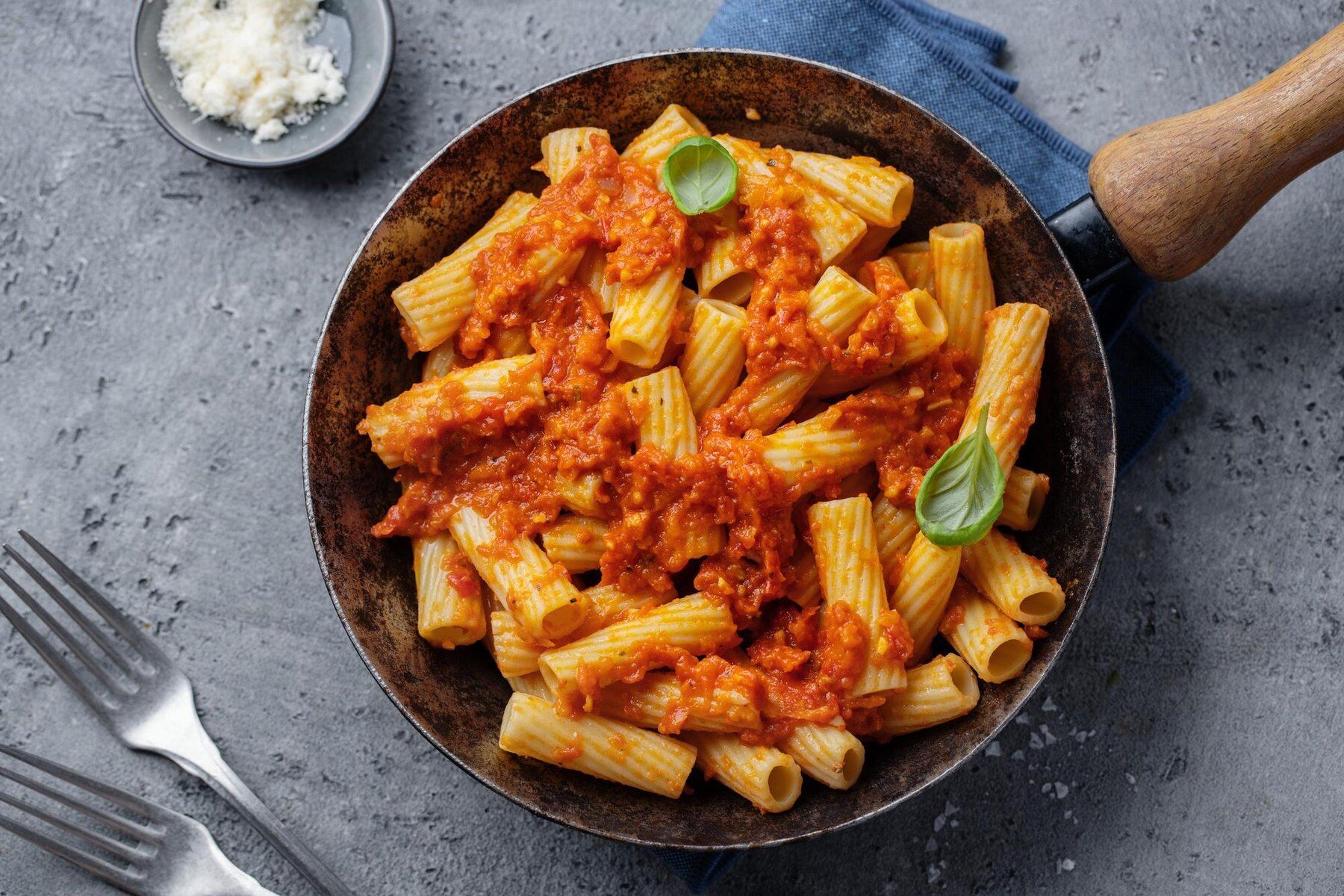 A pan filled with pasta and tomato sauce on a table.