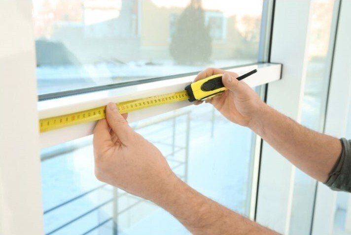 Handyman Contractor Surrey measuring out a window frame with a yellow tape measurer