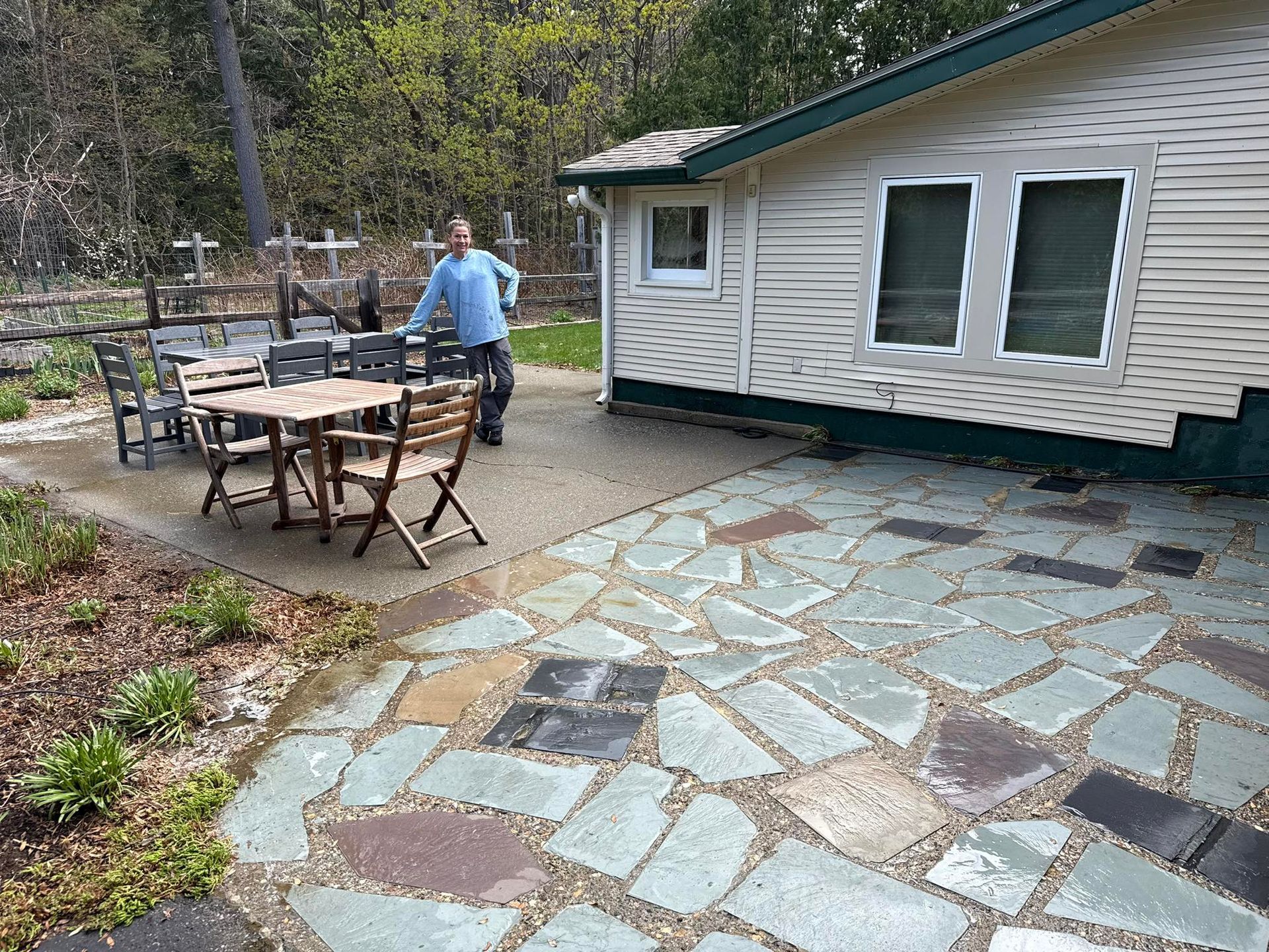 A man is standing on a stone patio in front of a house cleaned by Home Shine.
