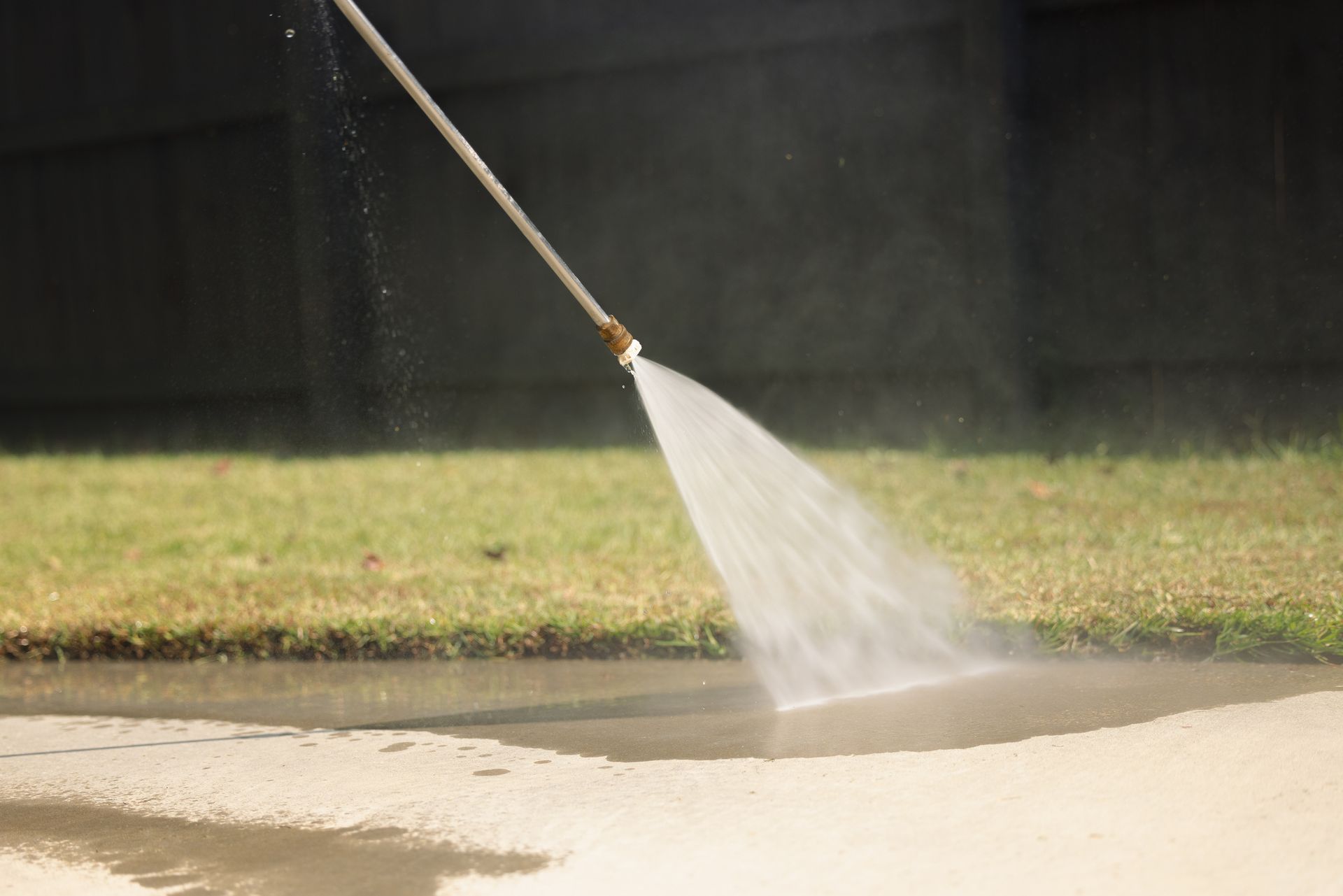 A person is using a high pressure washer to clean a concrete driveway.