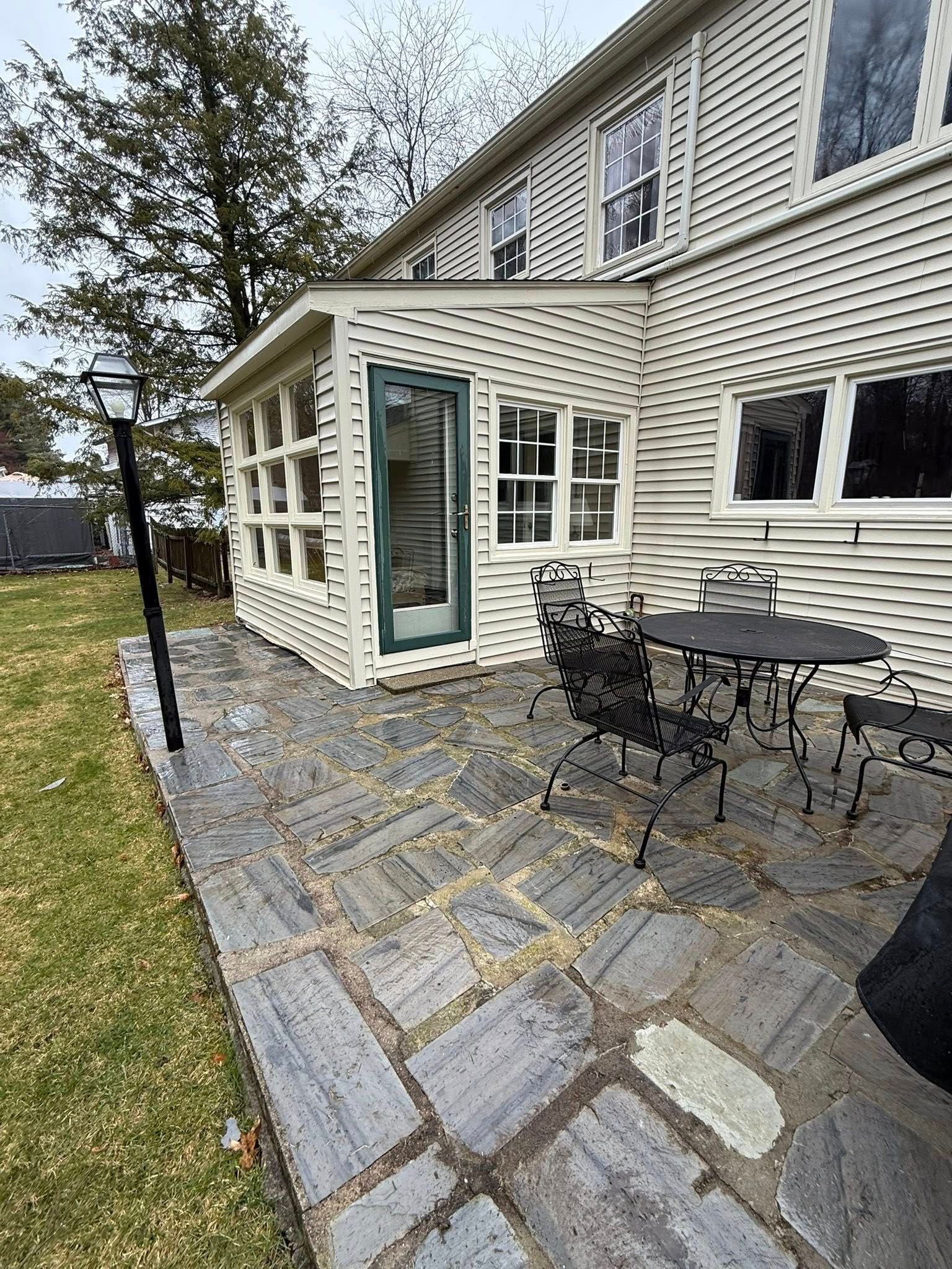 A patio with a table and chairs in front of a house cleaned by Home Shine