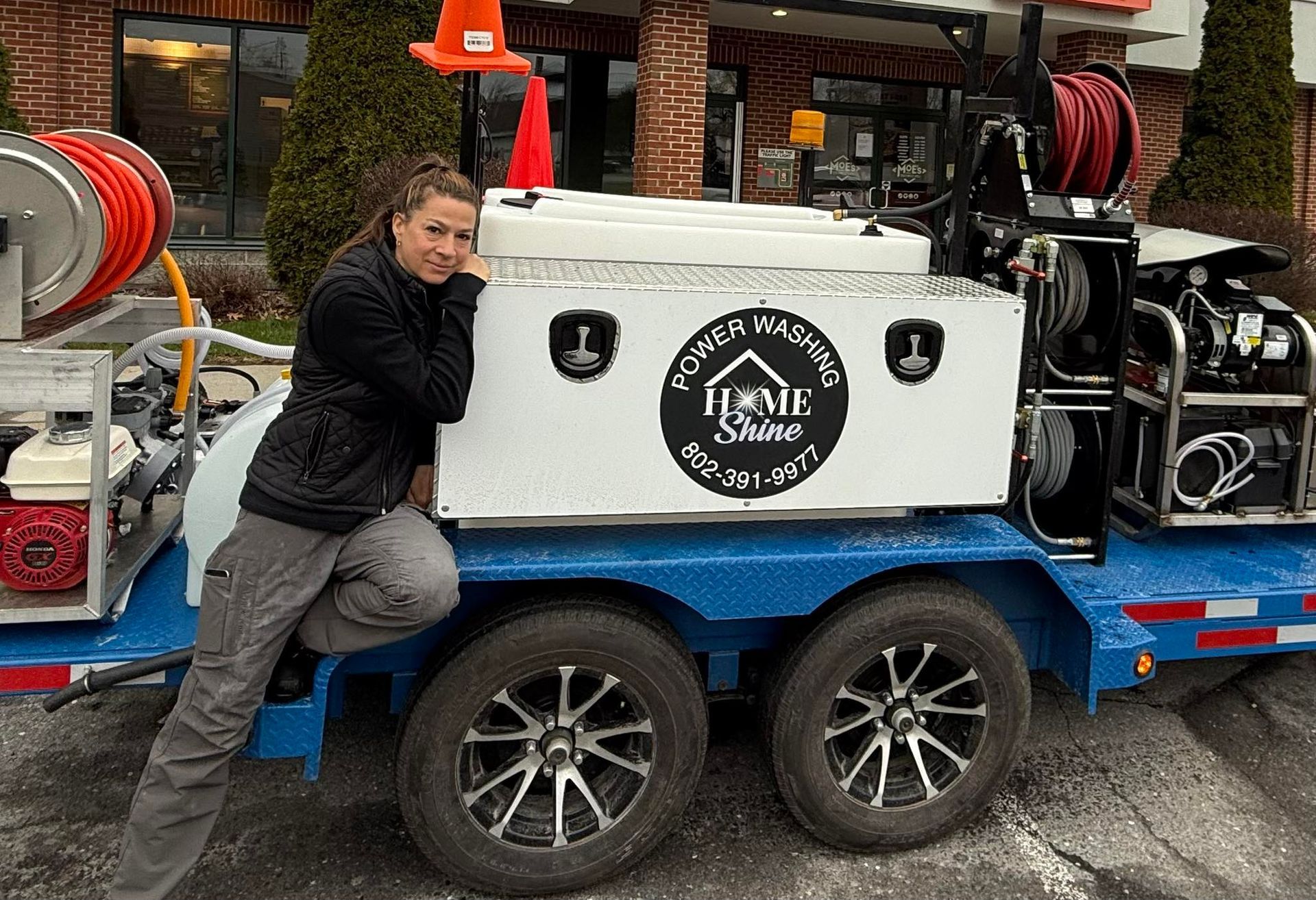 A Home Shine Employee is kneeling on a trailer with a hose attached to it.