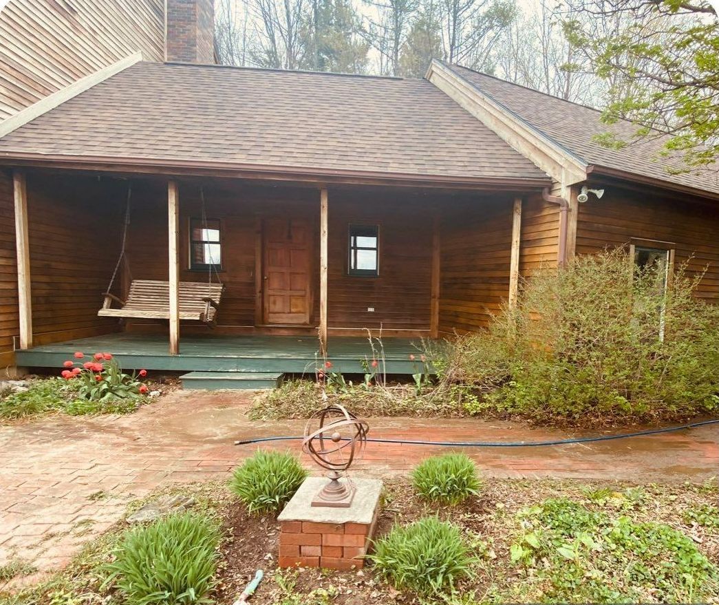 A log cabin with a porch and a swing on it.