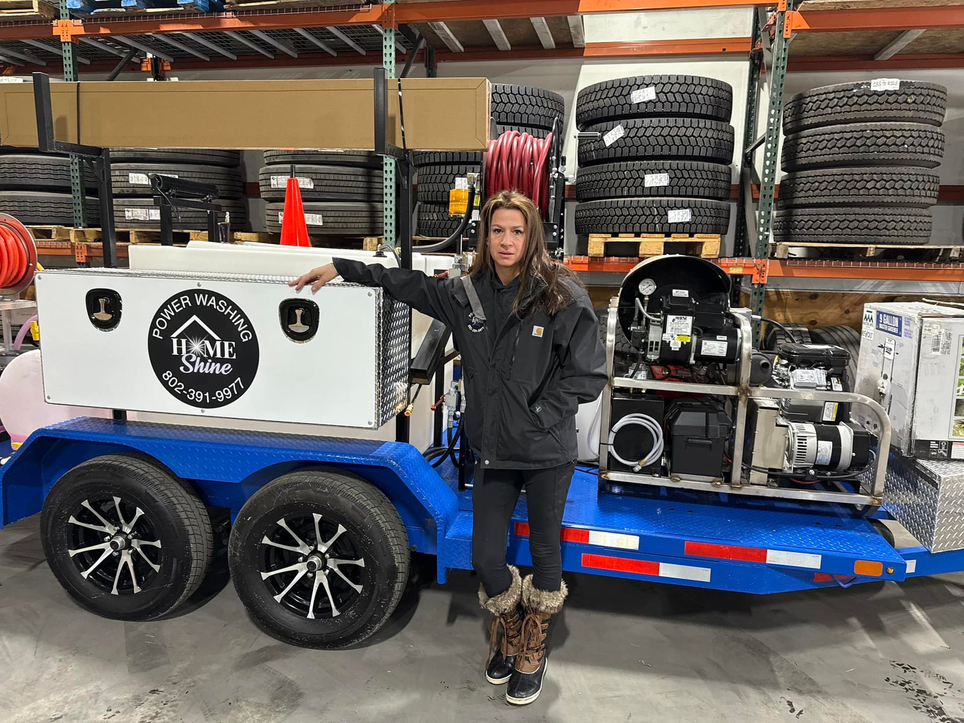 A woman is standing next to a trailer in a warehouse.