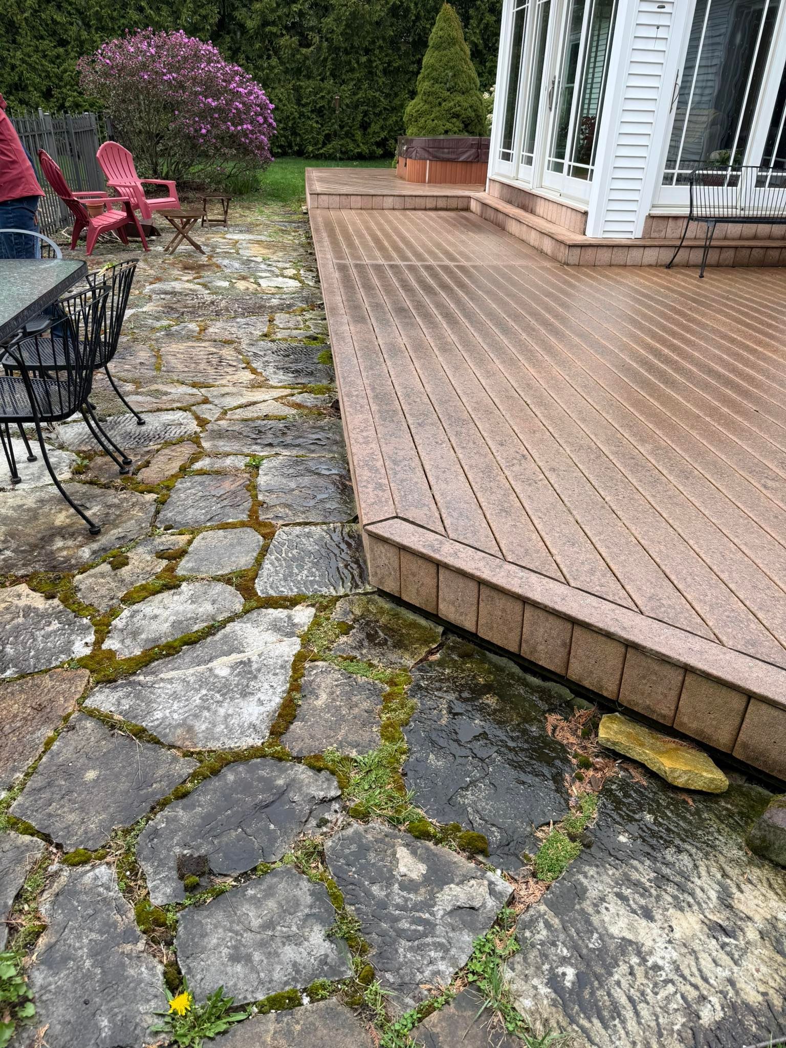 A patio with a wooden deck and a stone walkway leading to it.