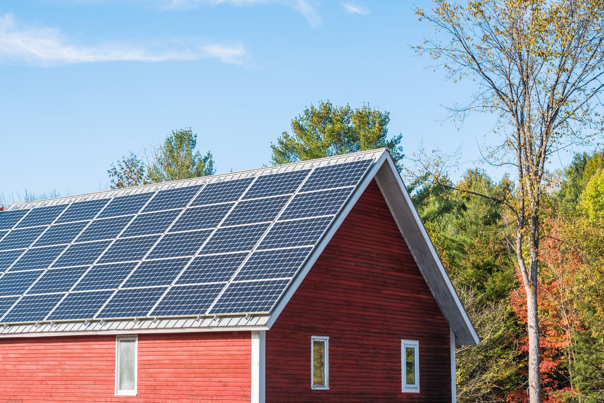 A red barn with solar panels on the roof cleaned by Home Shine.