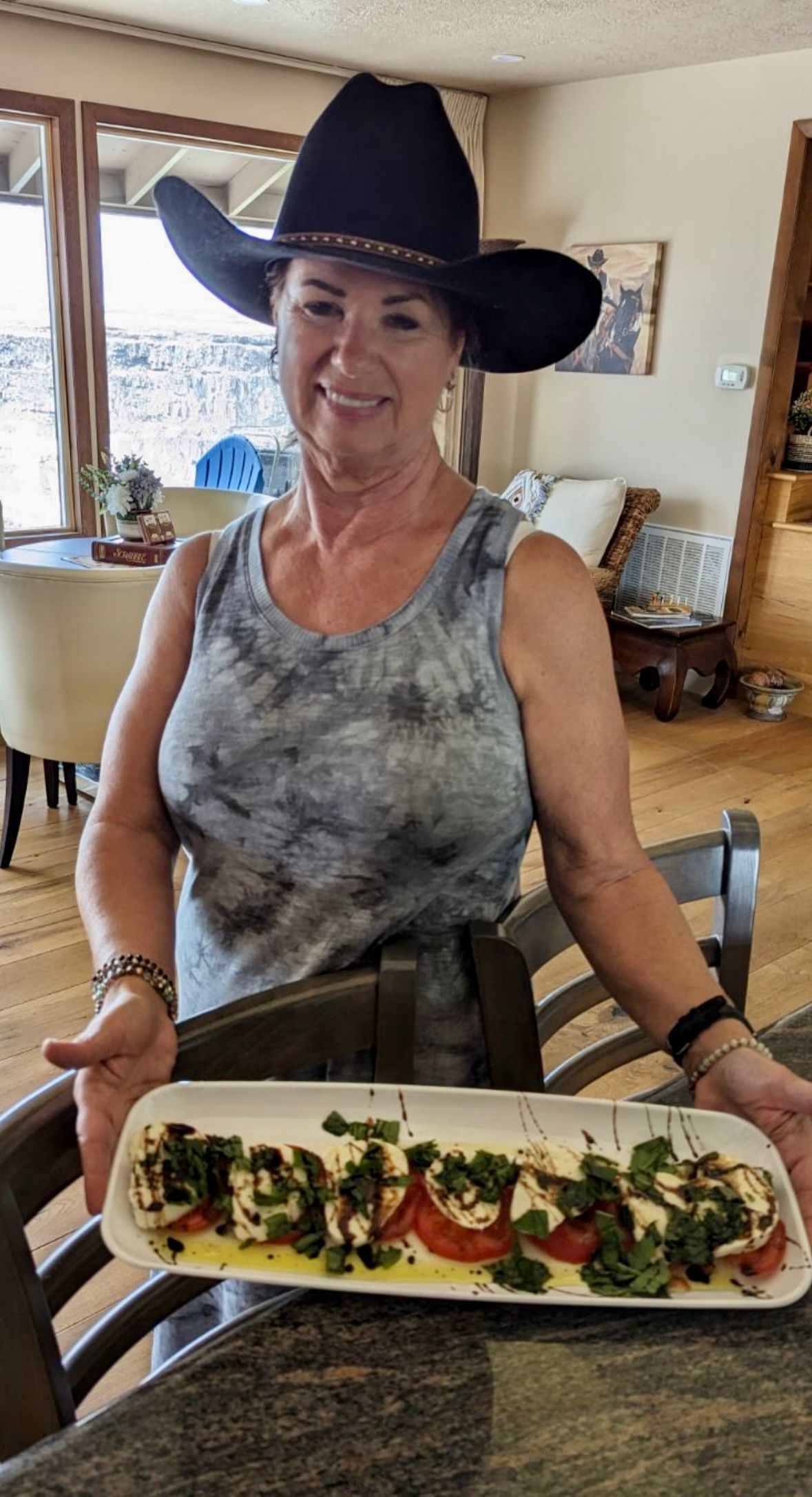 A woman wearing a cowboy hat is holding a plate of food.