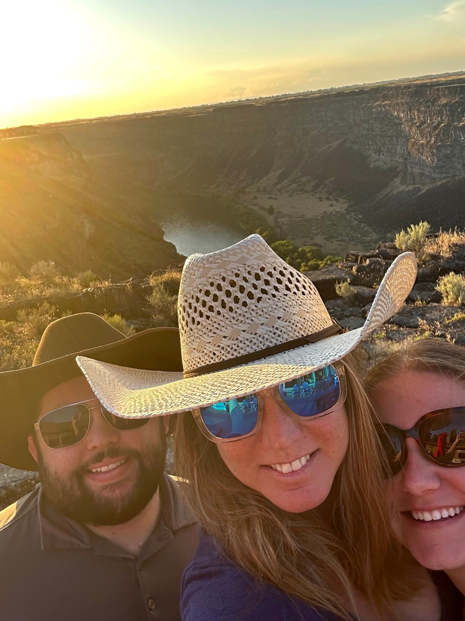 A man and two women wearing cowboy hats and sunglasses are posing for a picture.