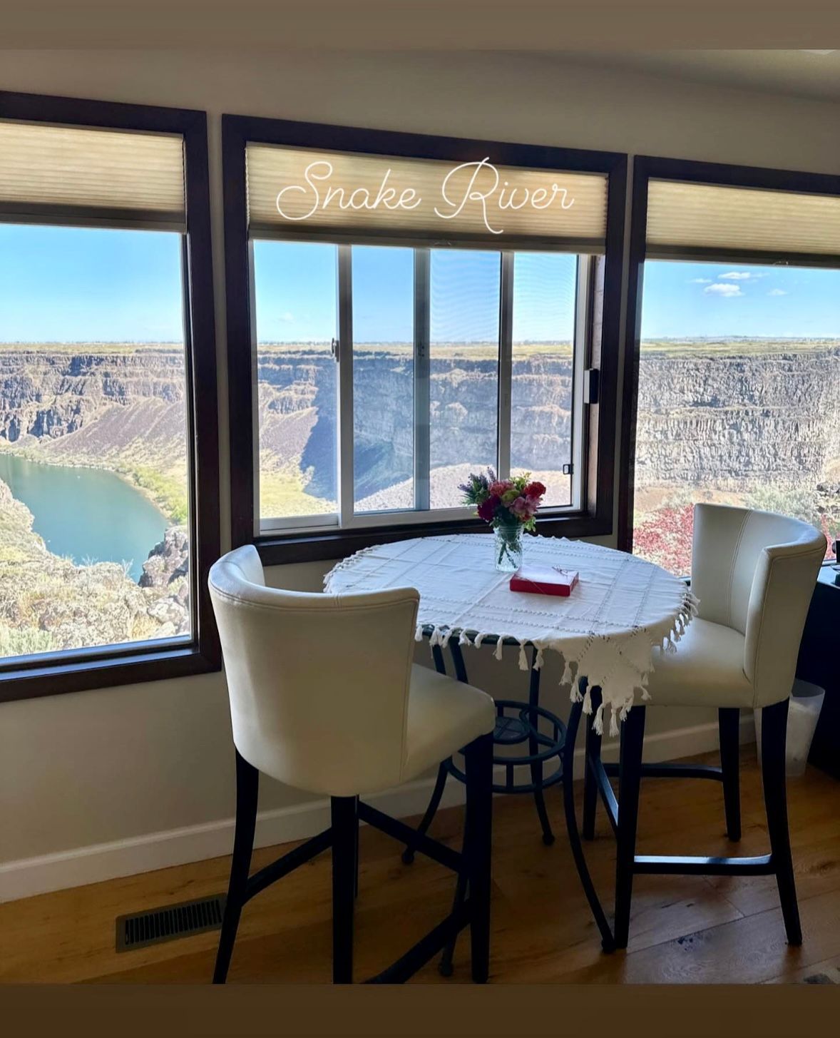 A room with a table and chairs with a view of snake river