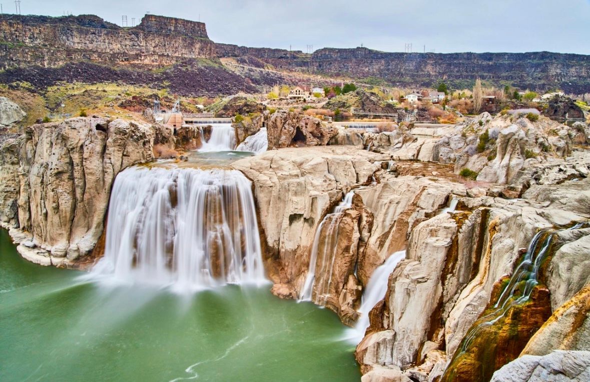 A waterfall in the middle of a canyon surrounded by rocks and water.