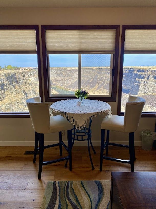A table and chairs in front of a window with a view of a canyon.