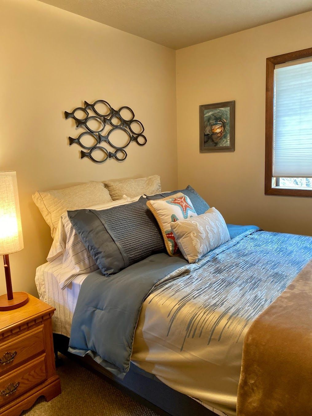 A bedroom with a bed , nightstand , lamp and window.