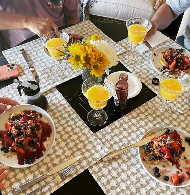A group of people are sitting at a table with plates of food and drinks.