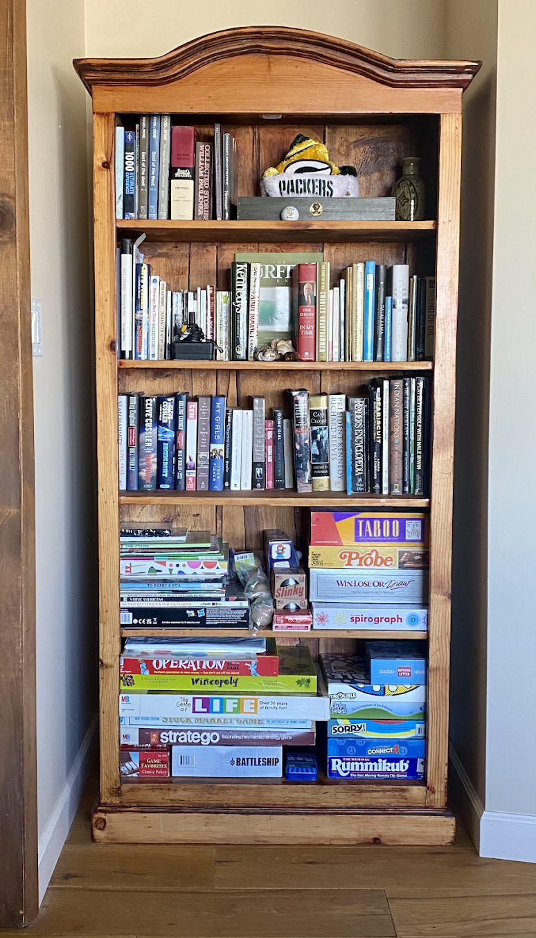 A bookshelf filled with books and games in a room.