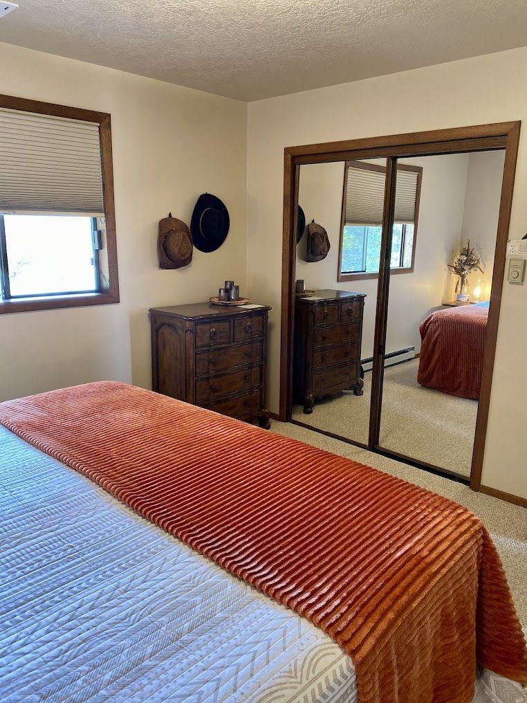 A bedroom with a bed , dresser , mirror and sliding glass doors.