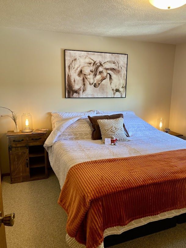 A bedroom with a large bed and a painting on the wall above it