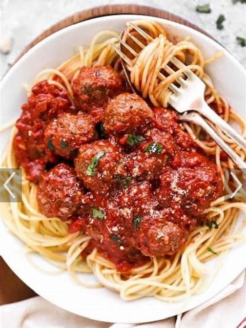 A white plate topped with spaghetti and meatballs with a fork.