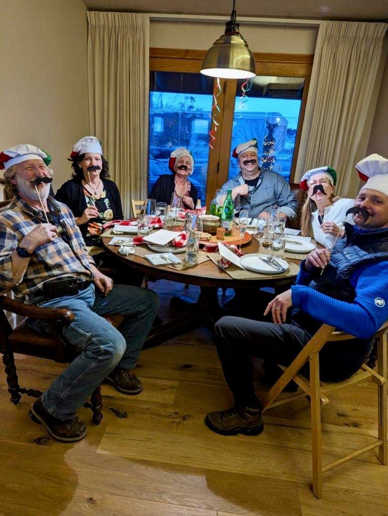 A group of people are sitting around a table wearing santa hats.