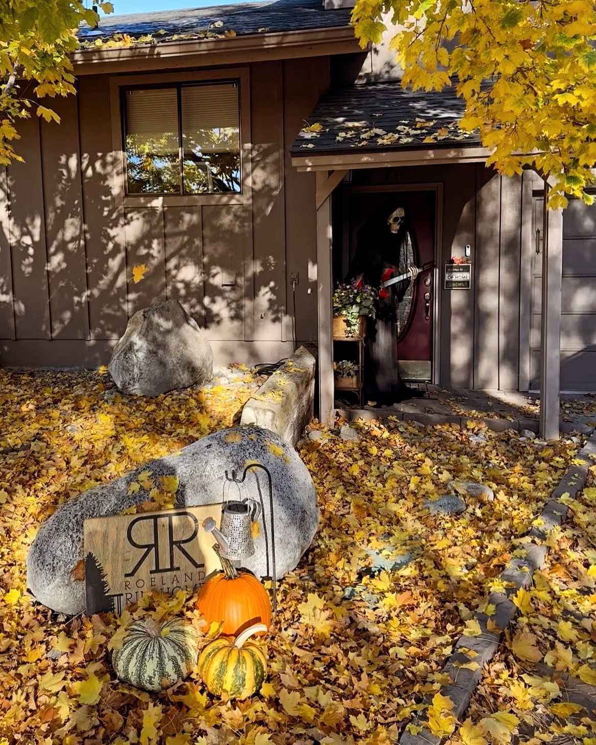 A house with pumpkins and leaves in front of it