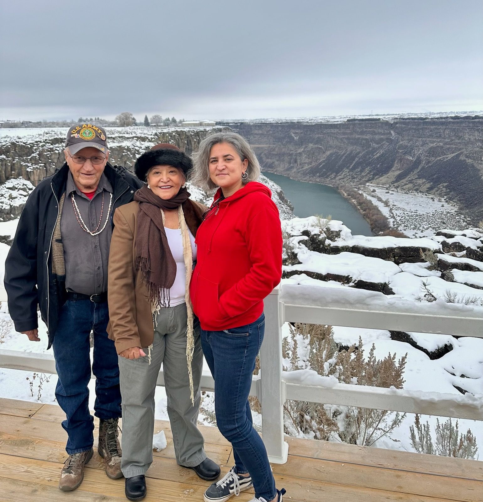 Three people posing for a picture in front of a snowy landscape