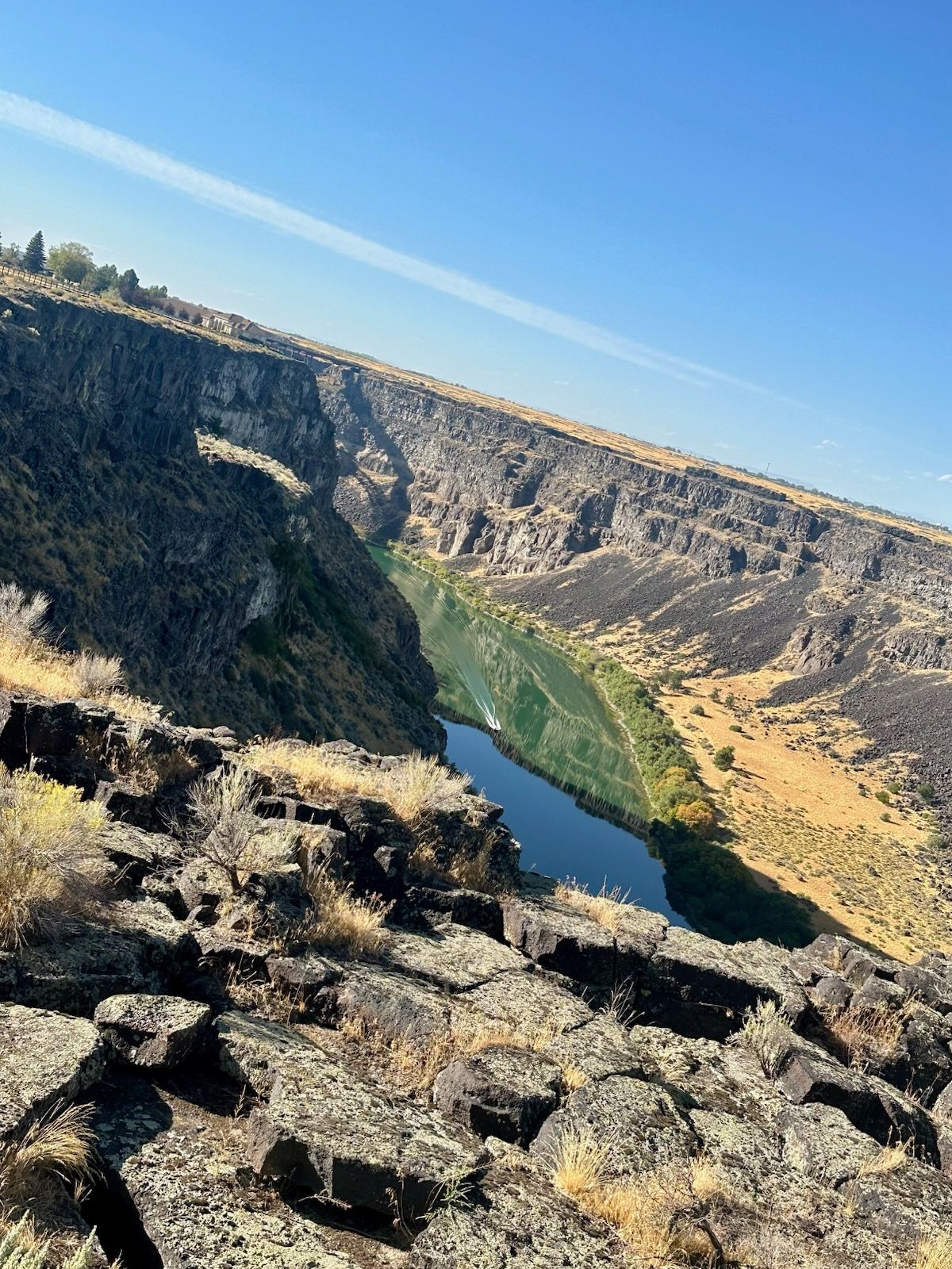 View of a river winding through a deep canyon. Rocky cliffs, blue water, and clear sky.