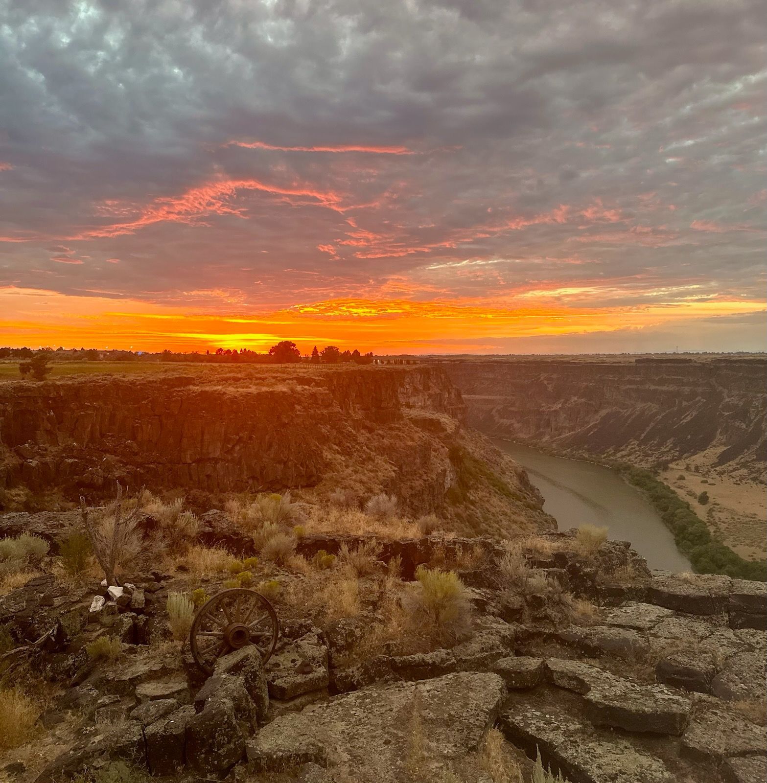 A sunset over a canyon with a river in the foreground.