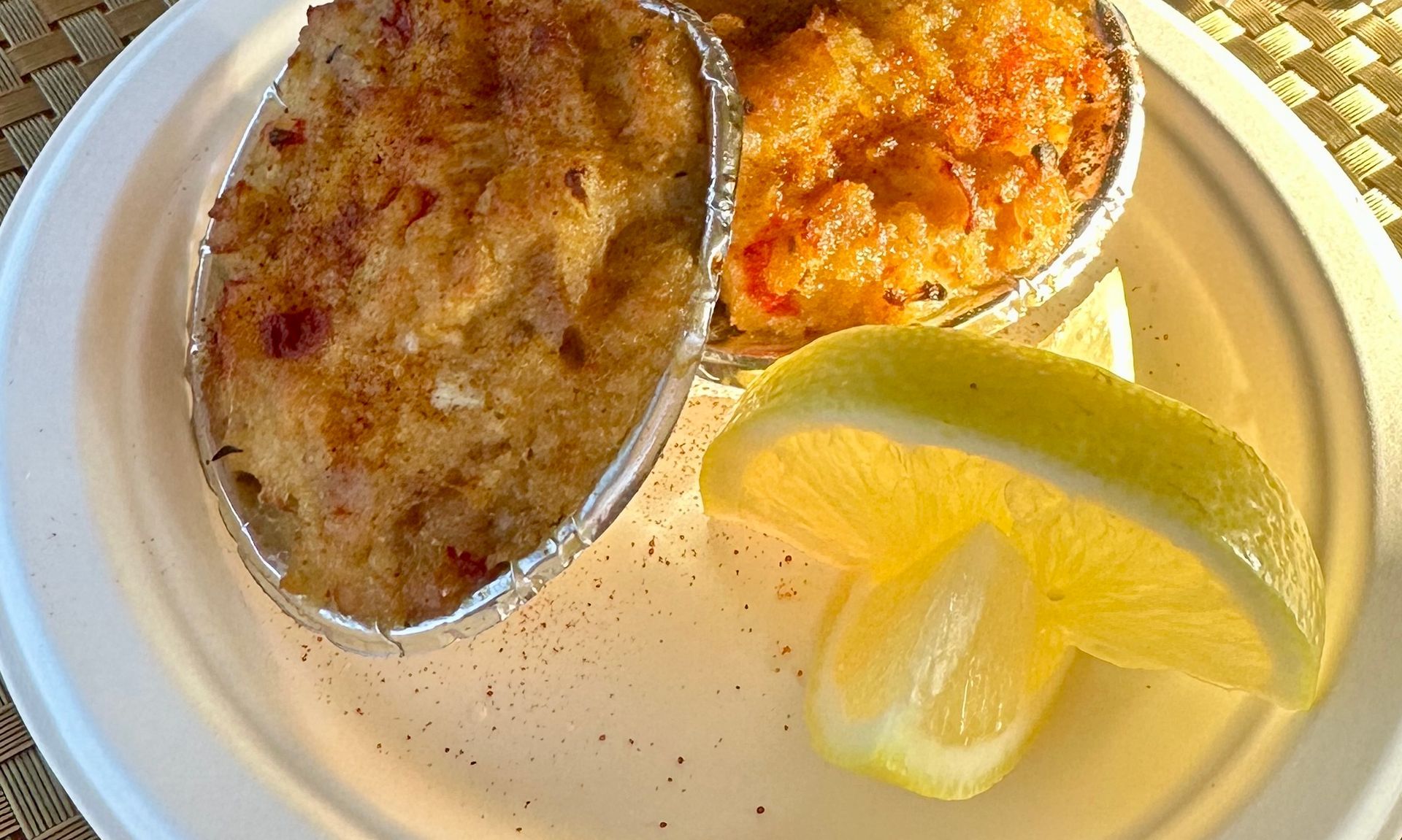 Two baked dishes with a lemon wedge on a white plate.