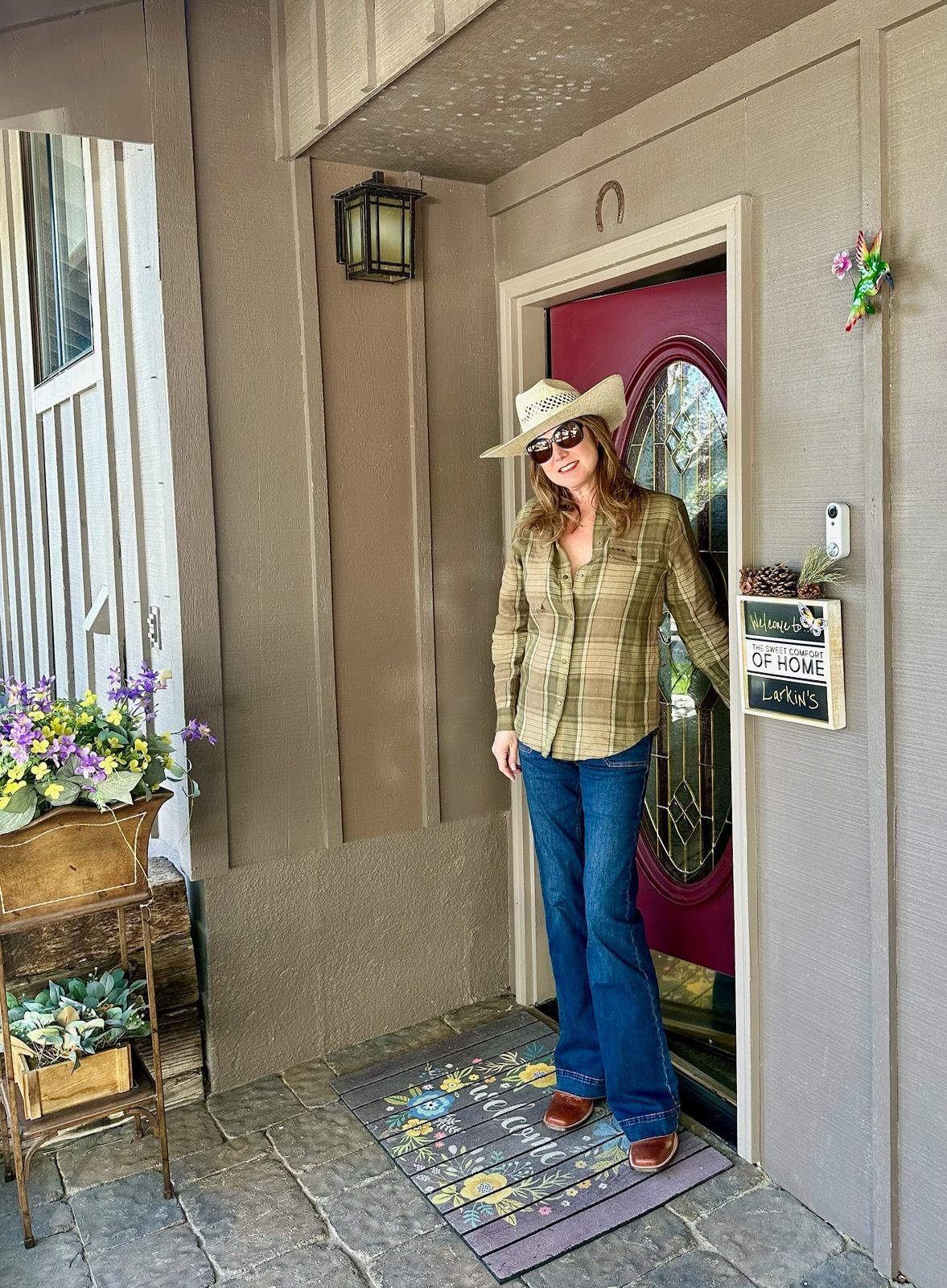 A woman in a cowboy hat is standing in front of a door.