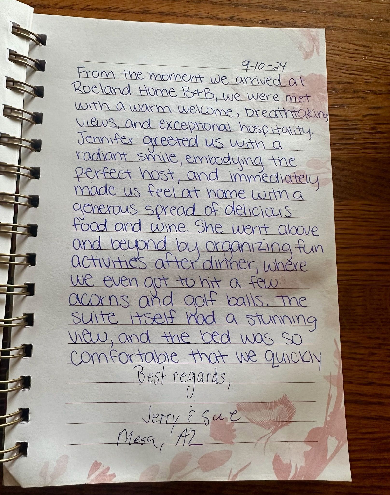Handwritten journal entry on a pink floral-decorated page; blue ink, spiral binding.