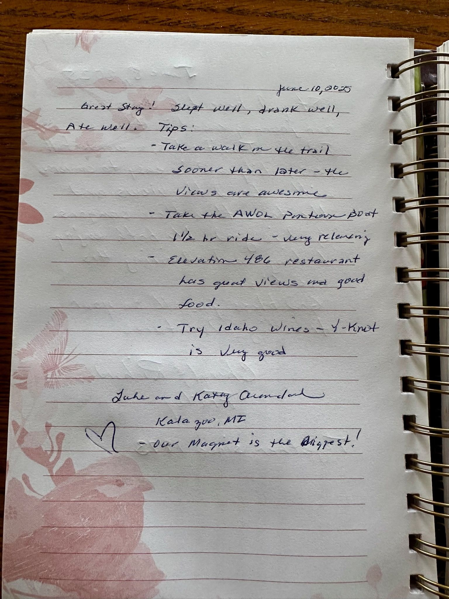 Notebook page with handwritten text, pink floral pattern, and spiral binding.