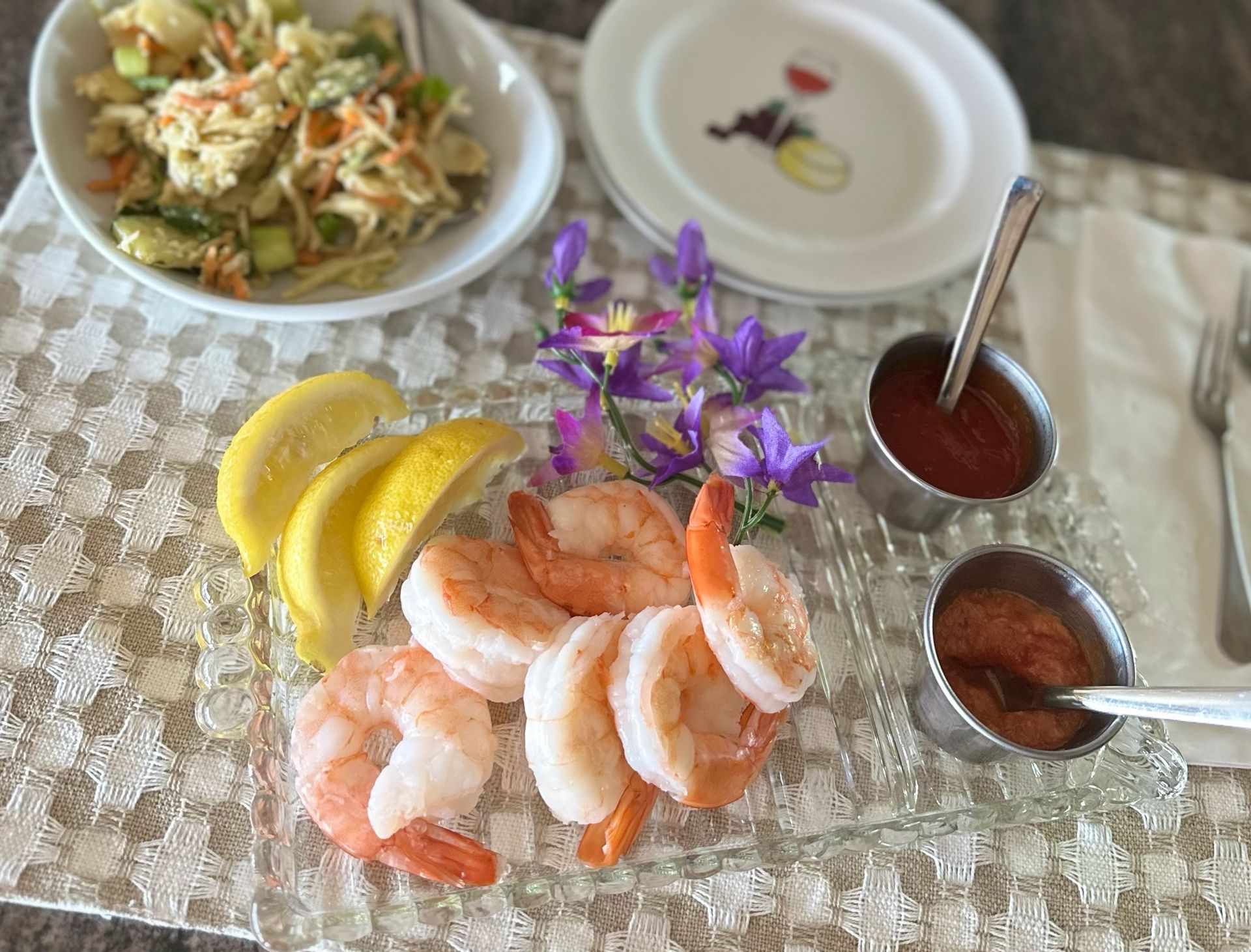 A plate of shrimp , lemon slices , and sauce on a table.