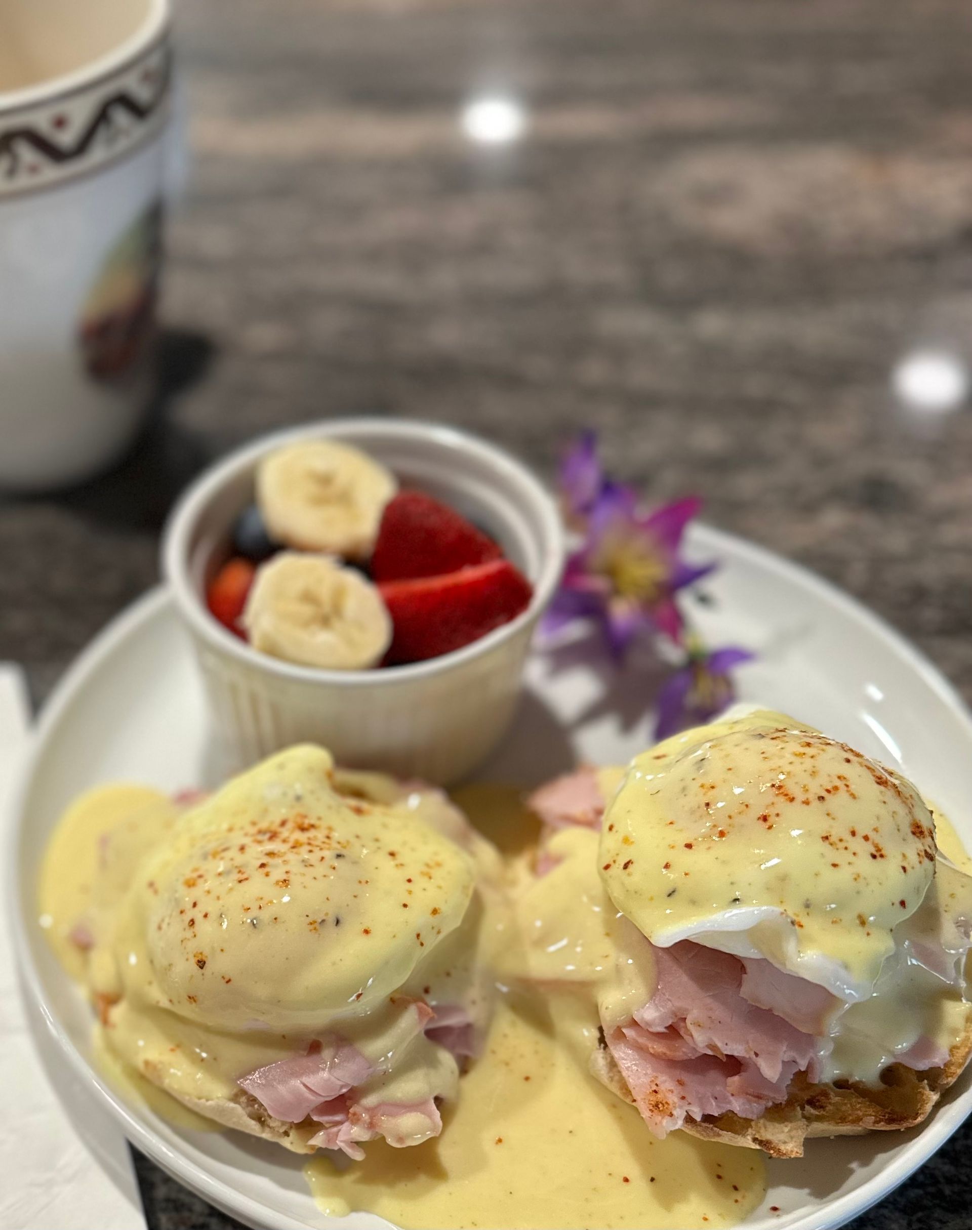 Eggs Benedict with fruit and coffee.