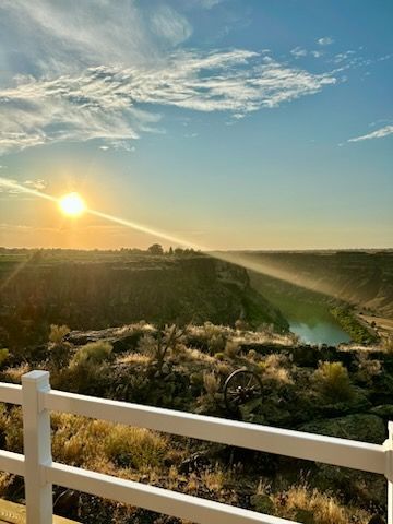 Sunset over a canyon with a river. White railing in the foreground.