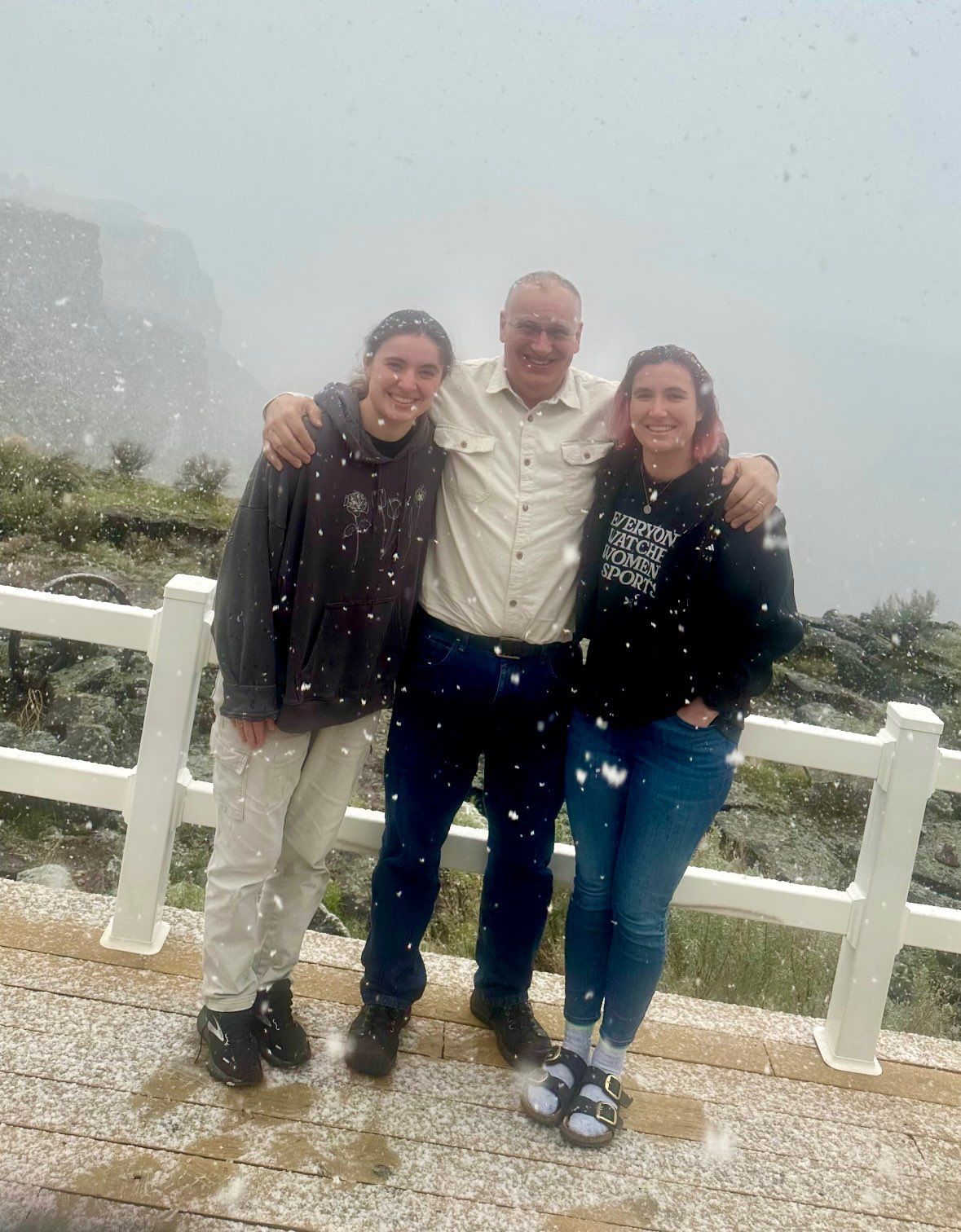 A man and two women are posing for a picture in the snow.