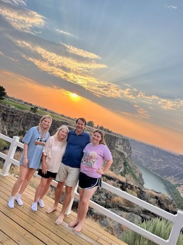 Family poses on a deck overlooking a canyon at sunset.