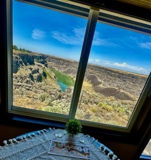 View through a window of a canyon landscape under a bright blue sky; table in the foreground.