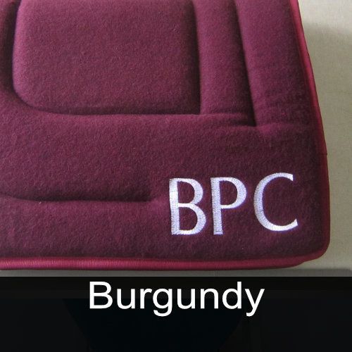 A burgundy pillow with the letters bpc embroidered on it