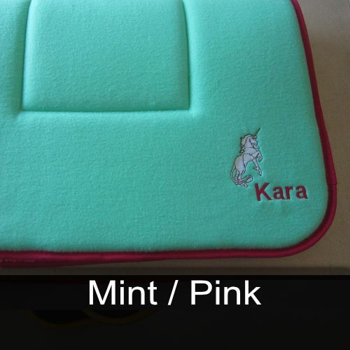 A green cushion with a unicorn and the name kara embroidered on it