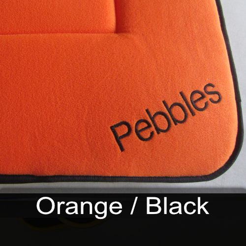 An orange cushion with the word pebbles embroidered on it
