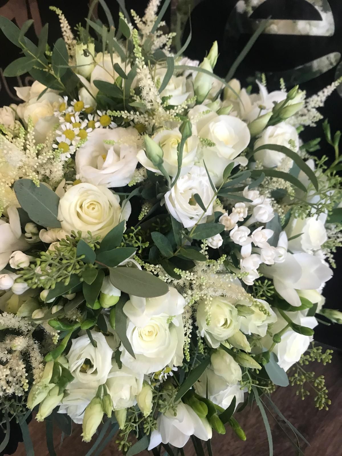White floral bouquet with roses, lisianthus, and greenery.