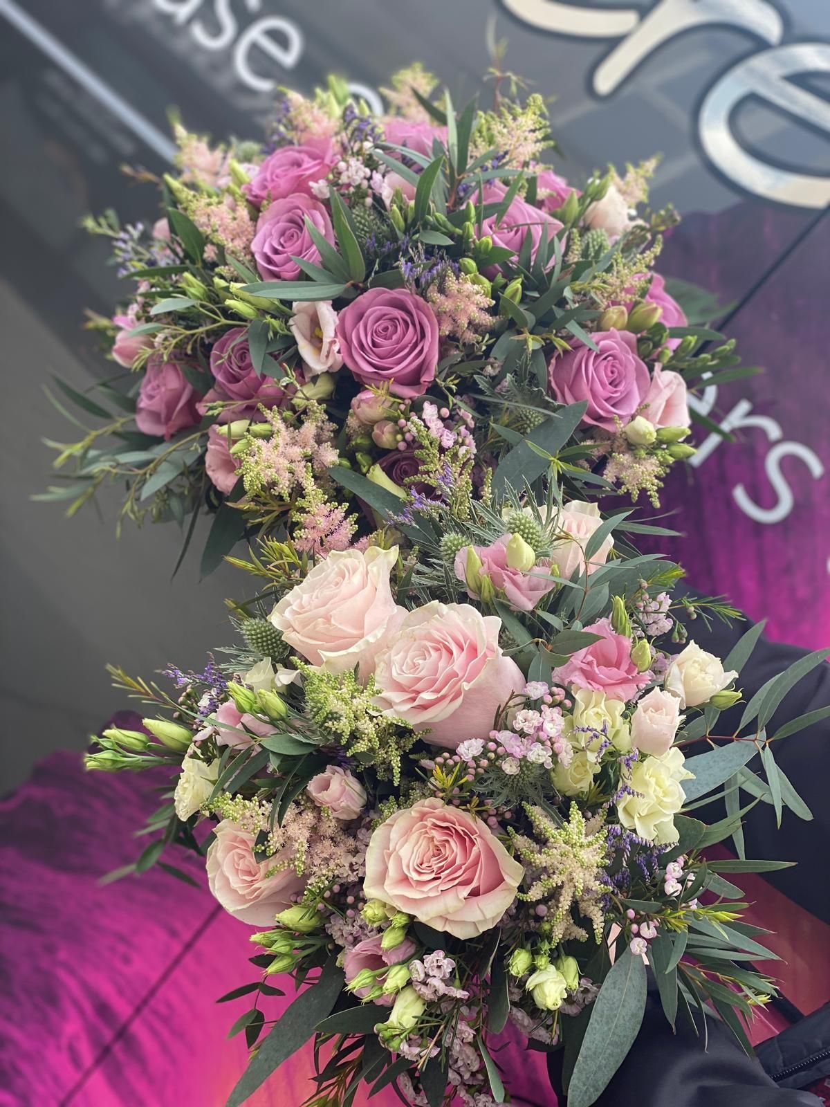 Two bouquets of pink and lavender flowers, held outdoors.