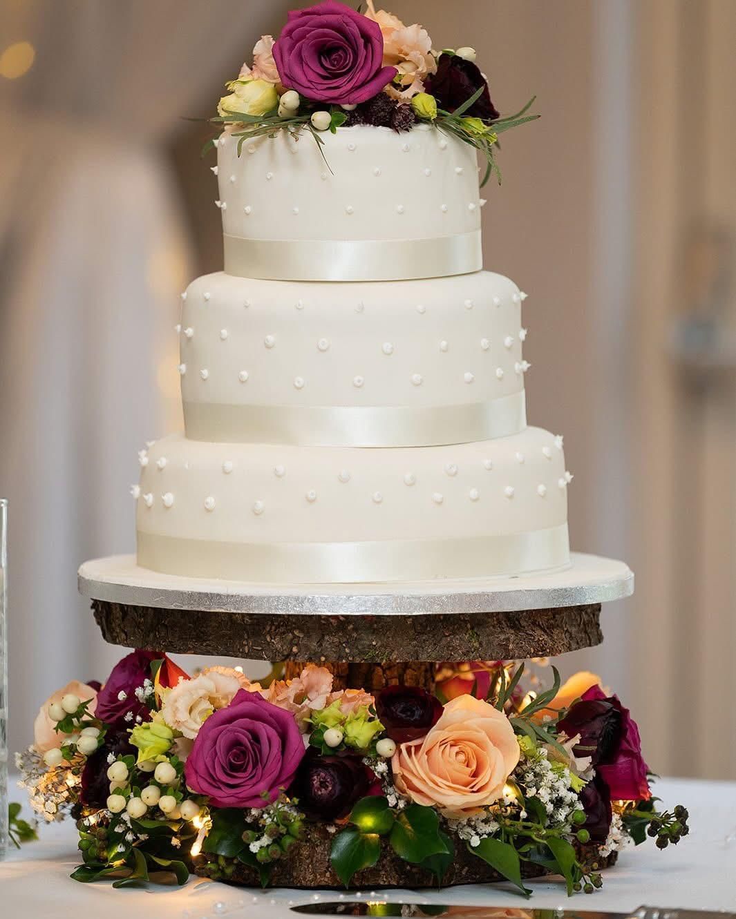 Three-tiered white wedding cake with dot texture, adorned with flowers