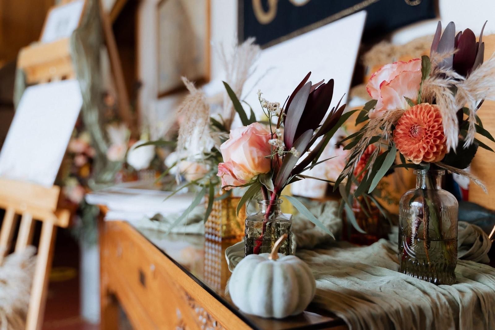 Floral arrangement with pumpkins and greenery on a wooden table.