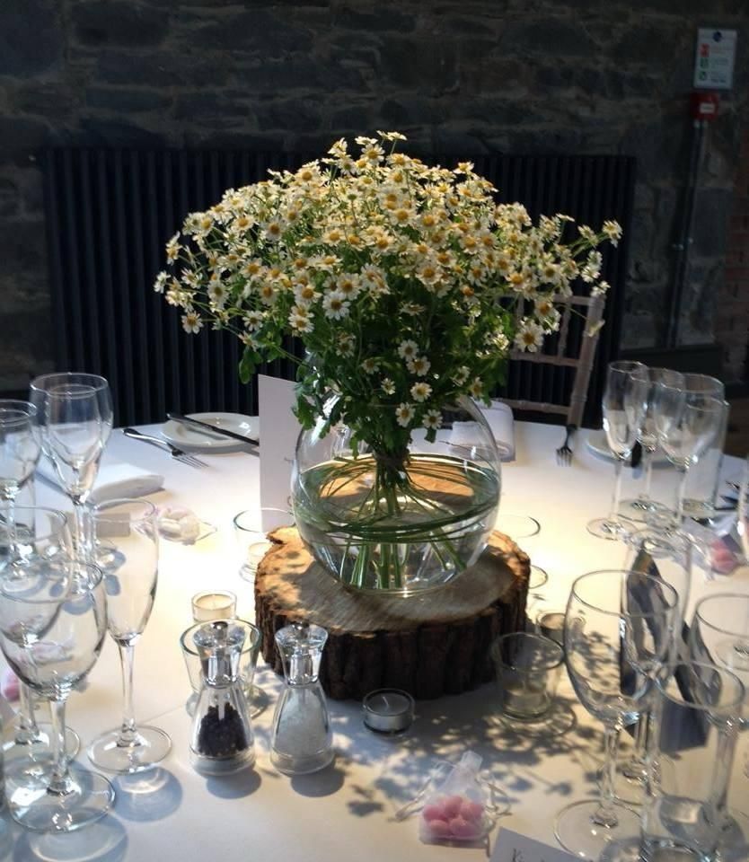 Wedding table with floral centerpiece in a glass bowl on a wood slice.