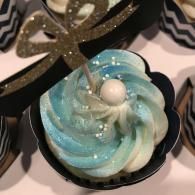 Blue and white swirled dessert with glittery topping in a black scalloped cup