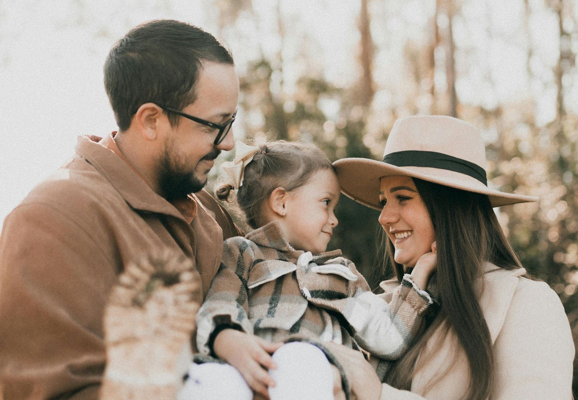 A man and woman are holding a little girl in their arms.