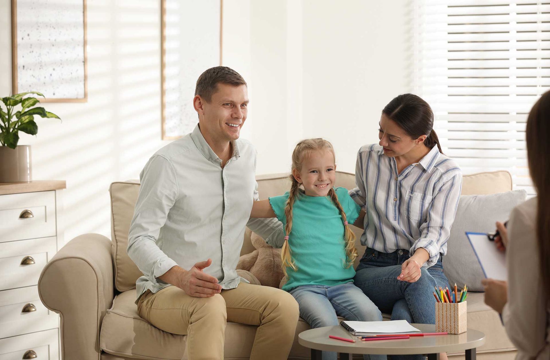 A family is sitting on a couch talking to a counselor.